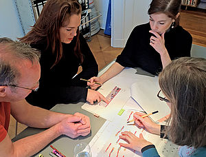 Das Projektteam sitzt am Tisch über Planungsunterlagen.